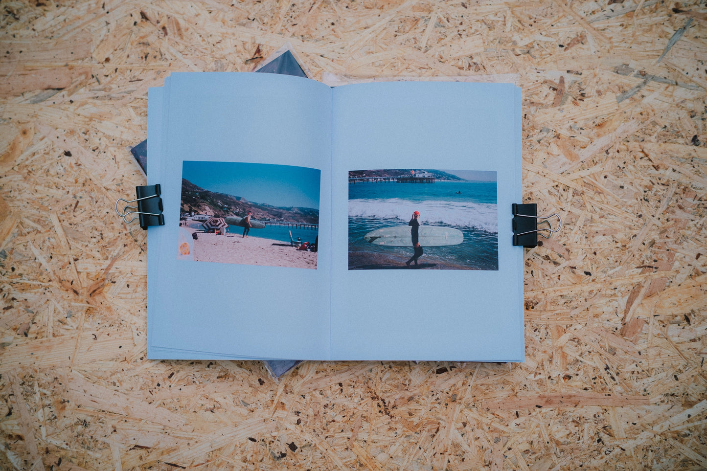 Open book with two photographs of a coastal scene on a wooden surface